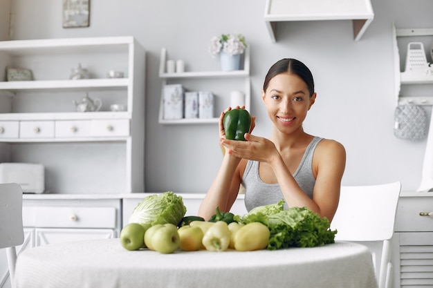 Free photo beautiful and sporty woman in a kitchen with vegetables