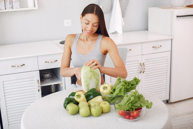 Beautiful and sporty woman in a kitchen with vegetables