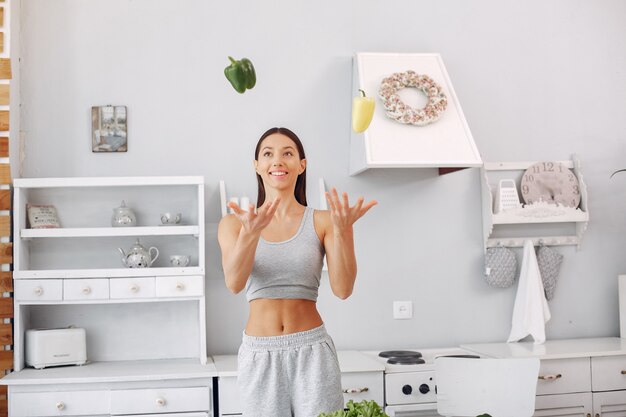 Beautiful and sporty woman in a kitchen with vegetables