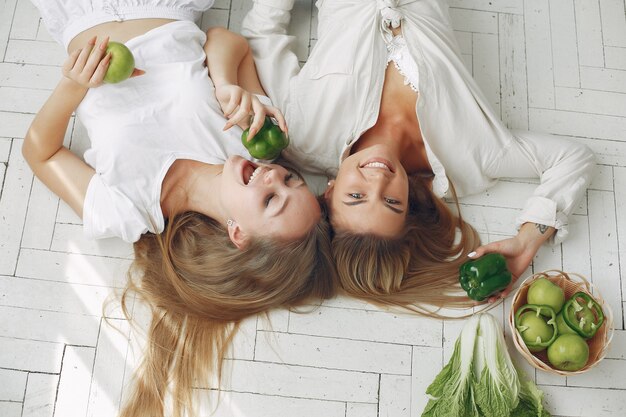 Beautiful and sporty women in a kitchen with vegetables