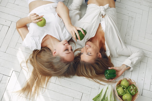 Beautiful and sporty women in a kitchen with vegetables