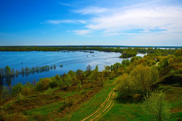 高い丘からの美しい春の風景。丘からの洪水の素晴らしい眺め。ヨーロッパ。ウクライナ。白い雲と印象的な青い空