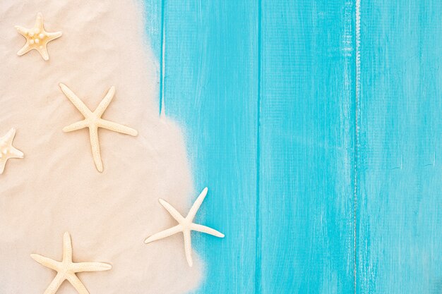 Красивые морские звезды с песком на деревянном синем фоне