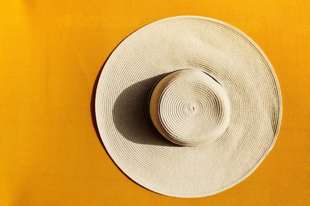 無料写真 黄色い鮮やかな鮮やかな背景に美しい麦わら帽子。上面図。