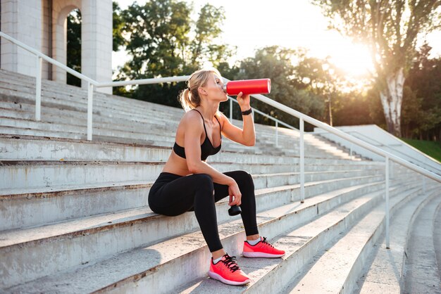 美しい強い若いスポーツ女性は水を飲む