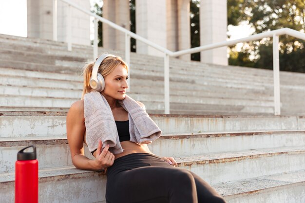 Beautiful strong young sports woman sitting on steps