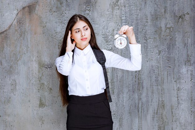 Beautiful student in formal outfit looking at time on clock. High quality photo