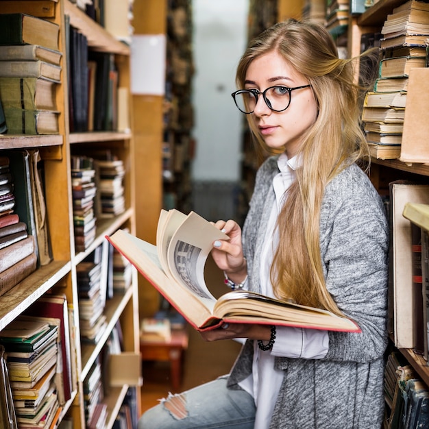 Foto gratuita bella studentessa che gira le pagine del libro