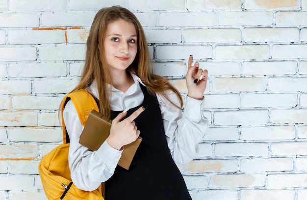 A beautiful student in uniform stands on a white background and point fingers aside High quality photo