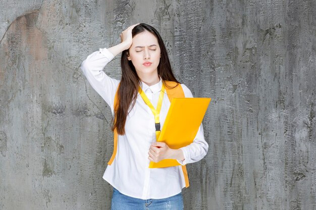 Beautiful student in white shirt holding book and having headache. High quality photo