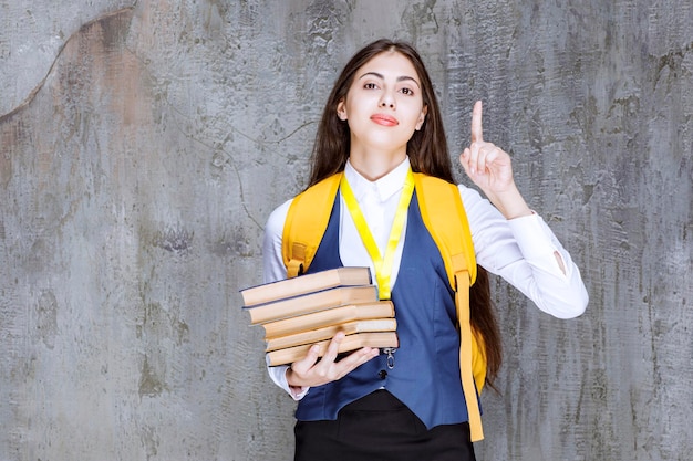 Beautiful student with books pointing at something. high quality photo