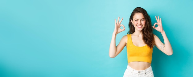 Free photo beautiful and stylish confident woman showing okay signs approve good choice wearing summer clothes standing over blue background
