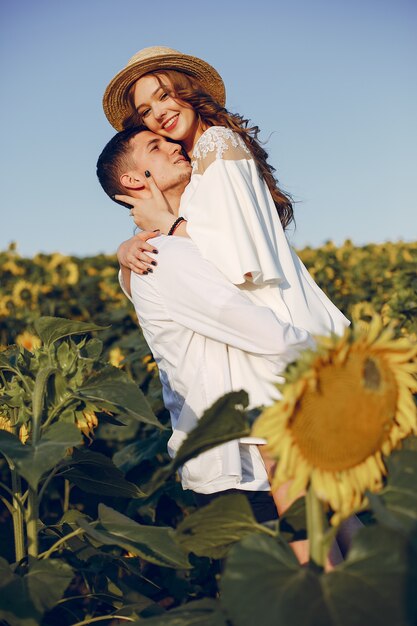 Coppia bella ed elegante in un campo con girasoli