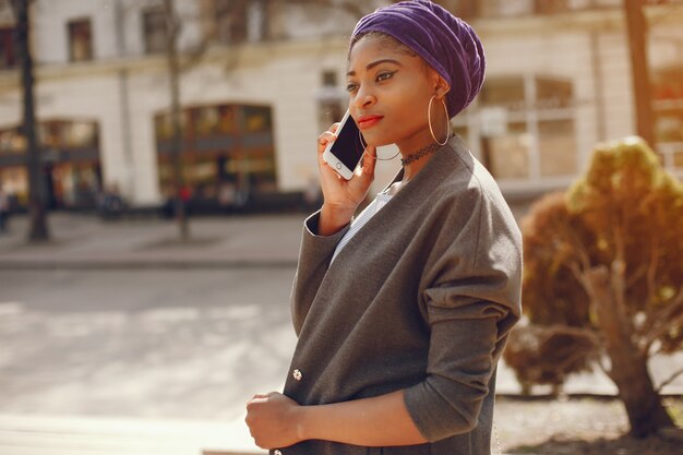 A beautiful and stylish dark-skinned girl walks in a sunny summer city