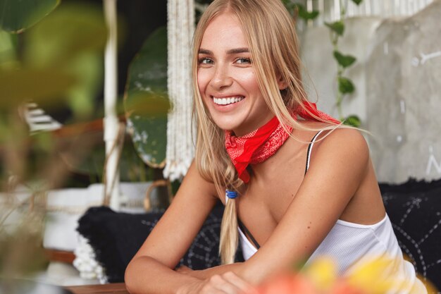 Bella donna alla moda indossa bandana rossa sul collo sul caffè