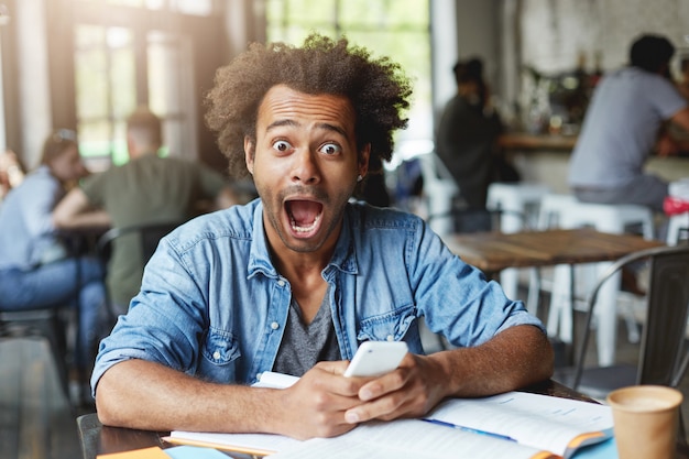 Beautiful stylish young African male student having surprised expression