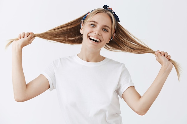 Beautiful stylish young blond girl posing against the white wall