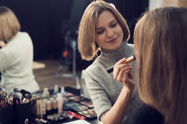 Beautiful stylist applying powder on model