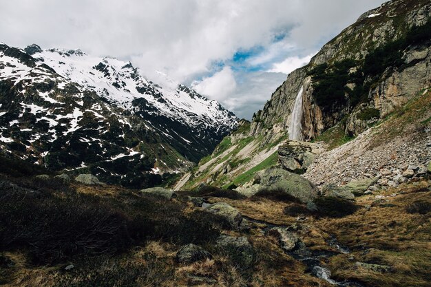 美しい夏山の中の滝のアルパインの風景