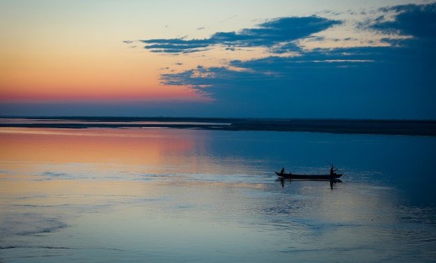 Beautiful sunset above the sea The silhouette of a boat floating on the water surface