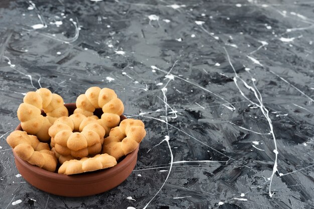 Beautiful sweet cookies for tea in a clay bowl on a marble surface 
