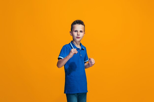 Beautiful teen boy looking suprised isolated on orange