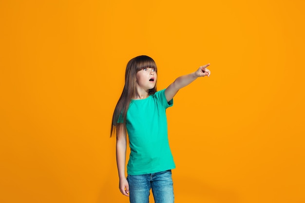 Beautiful teen girl looking suprised isolated on orange