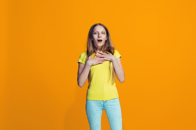 Beautiful teen girl looking suprised isolated on orange