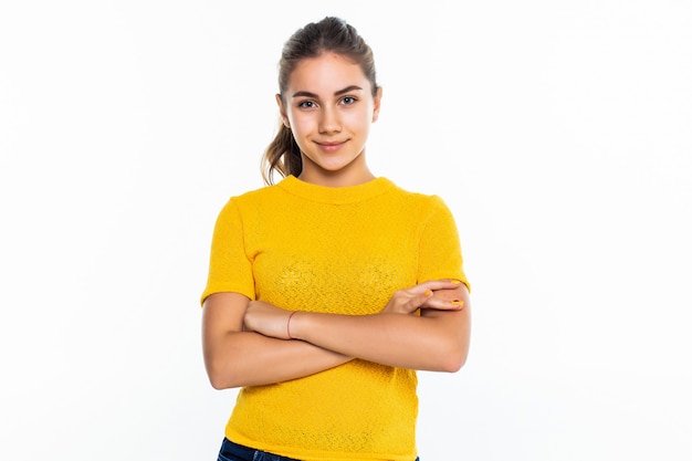 Beautiful teen girl student with confident expression, keeps arms folded. Portrait of smiling teenager isolated on white wall.