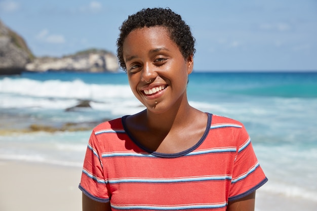 Beautiful teenage girl with curly boycut, smiles happily