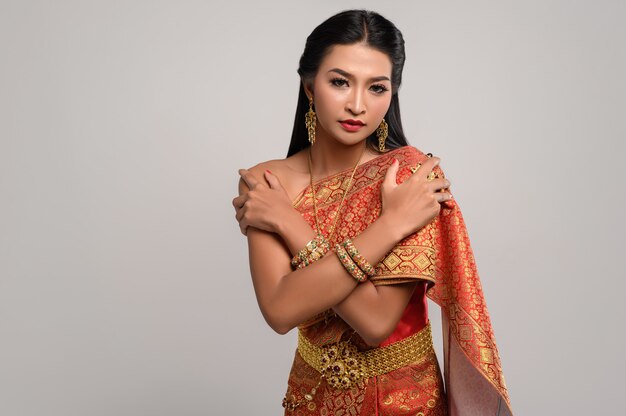 タイのドレスを着て、自分を抱いて立っている美しいタイの女性