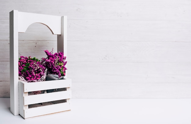 Free photo beautiful tiny purple flowers in crates on desk against wooden backdrop