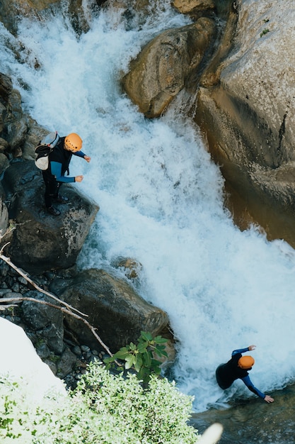 Красивый снимок с верхнего угла людей, занимающихся экстремальными видами спорта над рекой в каменистой горе
