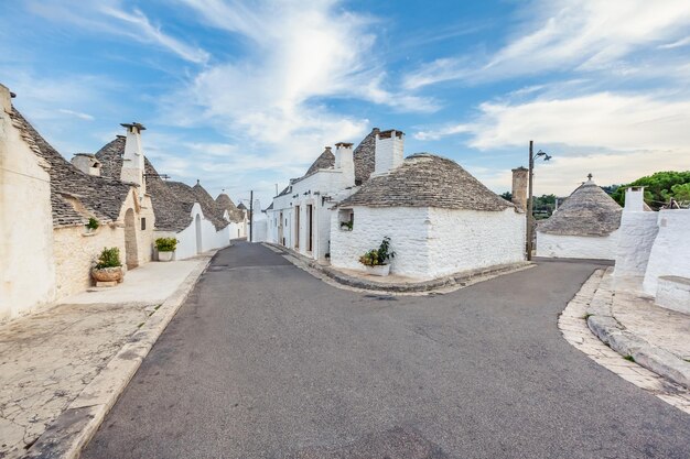 Beautiful town of Alberobello with Trulli houses among green plants and flowers, main touristic district, Apulia region, Southern Italy. Typical buildings built with a dry stone walls and conical roof