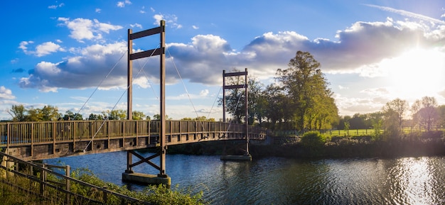 イギリス、ウィンザーの日没で川に架かる橋のある公園の美しい木