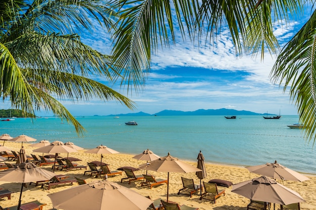 Beautiful tropical beach sea and ocean with coconut palm tree  and umbrella and chair on blue sky 