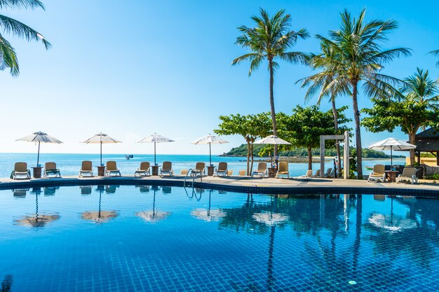 Beautiful tropical beach and sea with umbrella and chair around swimming pool