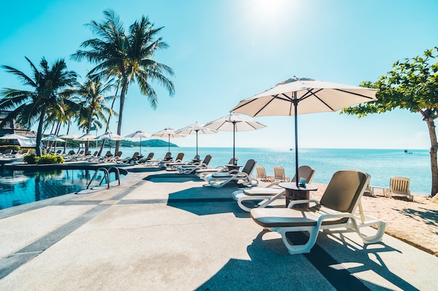 Beautiful tropical beach and sea with umbrella and chair around swimming pool