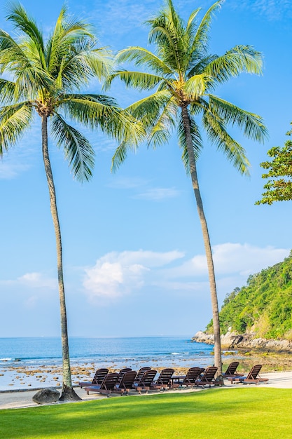 青い空に白い雲とビーチの海の周りの椅子と椅子と美しい熱帯のココヤシの木