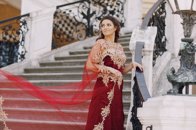 A beautiful Turkish girl in a long red dress walks in the summer old city