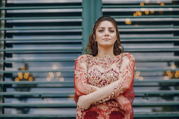 A beautiful Turkish girl in a long red dress walks in the summer old city