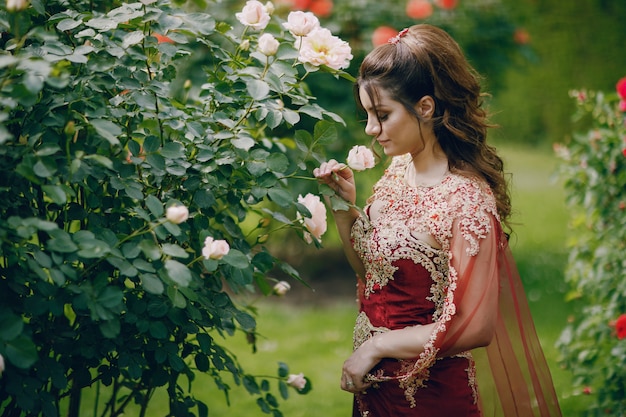 A beautiful Turkish girl in a long red dress walks in the summer old city