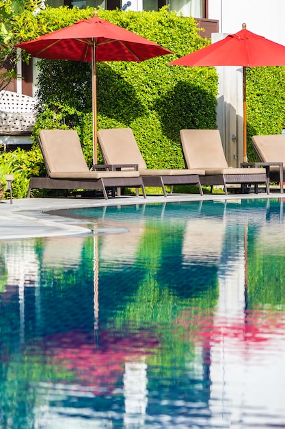 Bellissimo ombrellone e sedia intorno alla piscina all'aperto in hotel resort per viaggi di vacanza