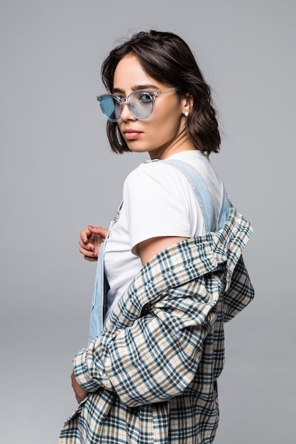 Beautiful urban woman wearing trendy sunglasses and sweater over shoulders, posing for advertising or promotion