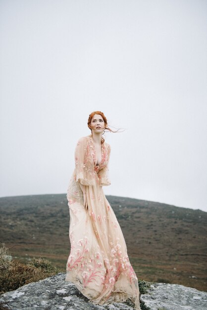 魅力的なピンクのガウンで真っ白な肌を持つ生姜の女性の美しい垂直画像
