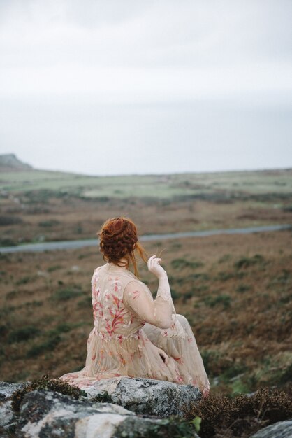 Beautiful vertical picture of a ginger female with a pure white skin in an attractive  pink gown