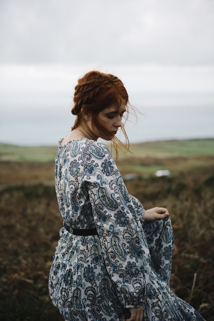 Beautiful vertical picture of a ginger female with a pure white skin in a light blue gown