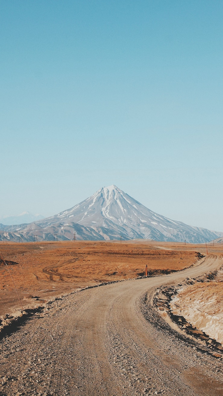 Free Photo beautiful vertical shot of a narrow curvy and muddy road with a high mountain