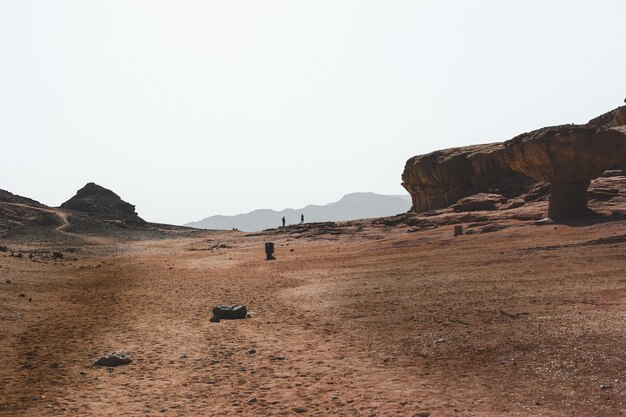 Beautiful view of the big rocks and dunes in a desert with the mountains in the background