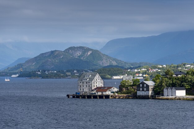 Прекрасный вид на здания на берегу недалеко от Олесунна, Норвегия с высокими горами